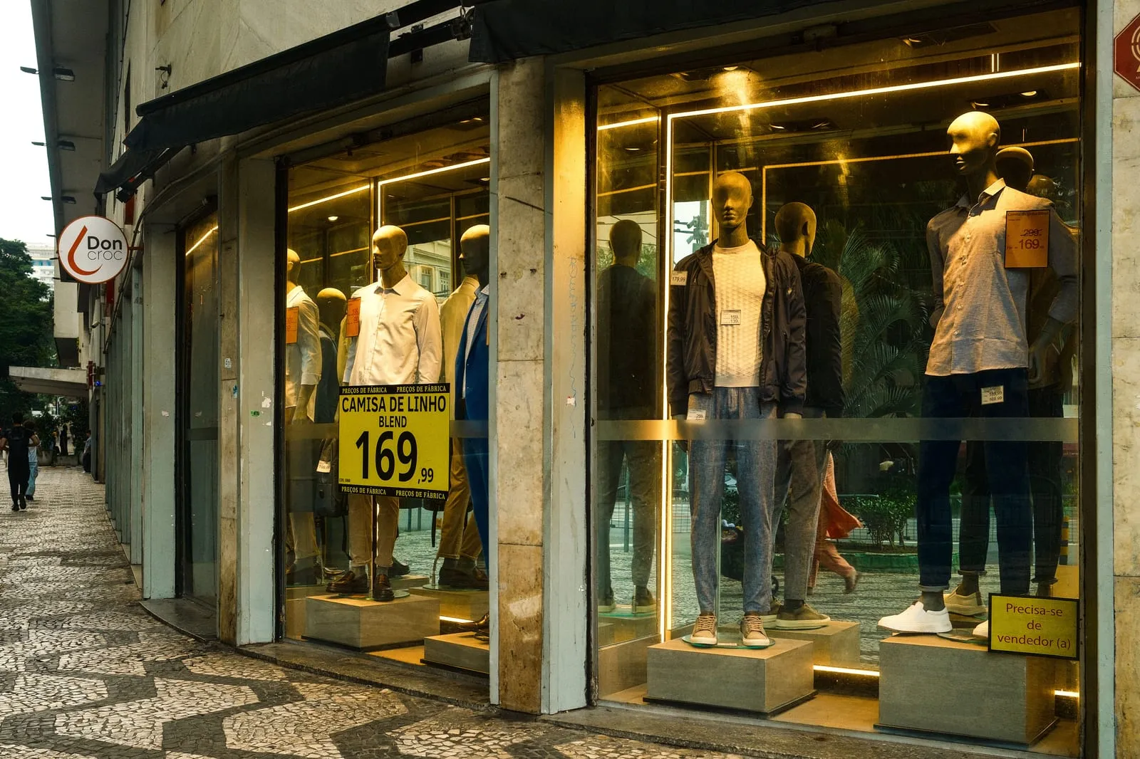 Vitrine de uma loja de roupas em uma rua comercial com calçada de pedra portuguesa