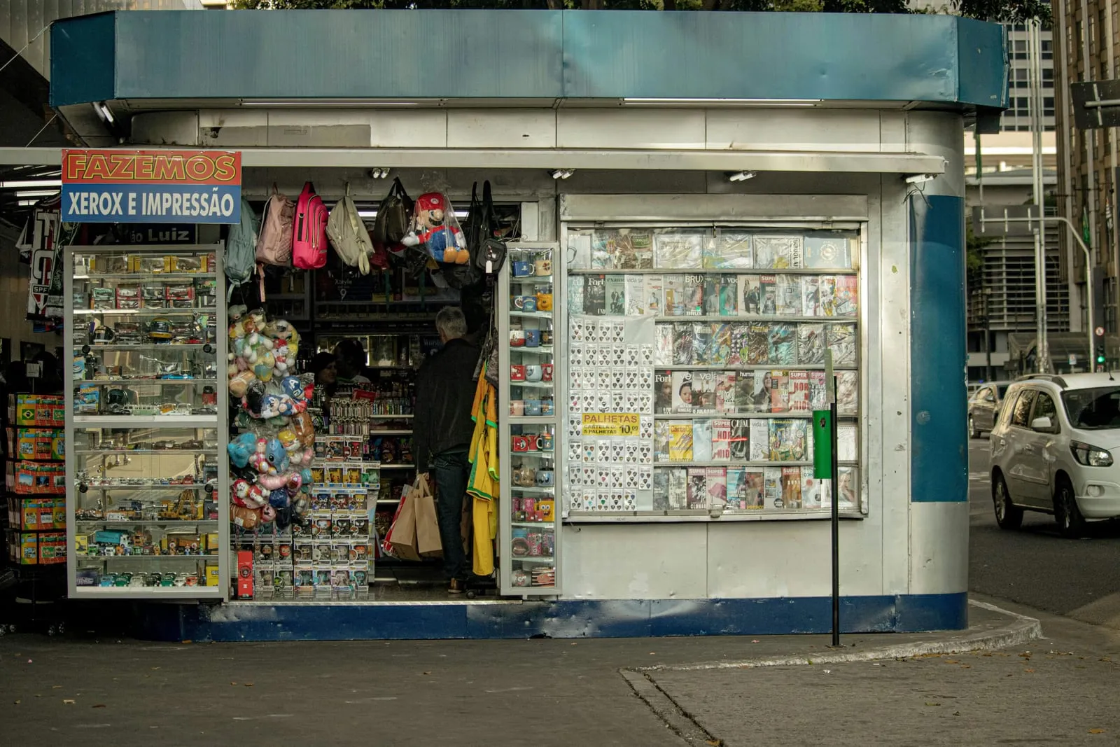 Banca de esquina com produtos expostos, que também oferece xerox e impressão
