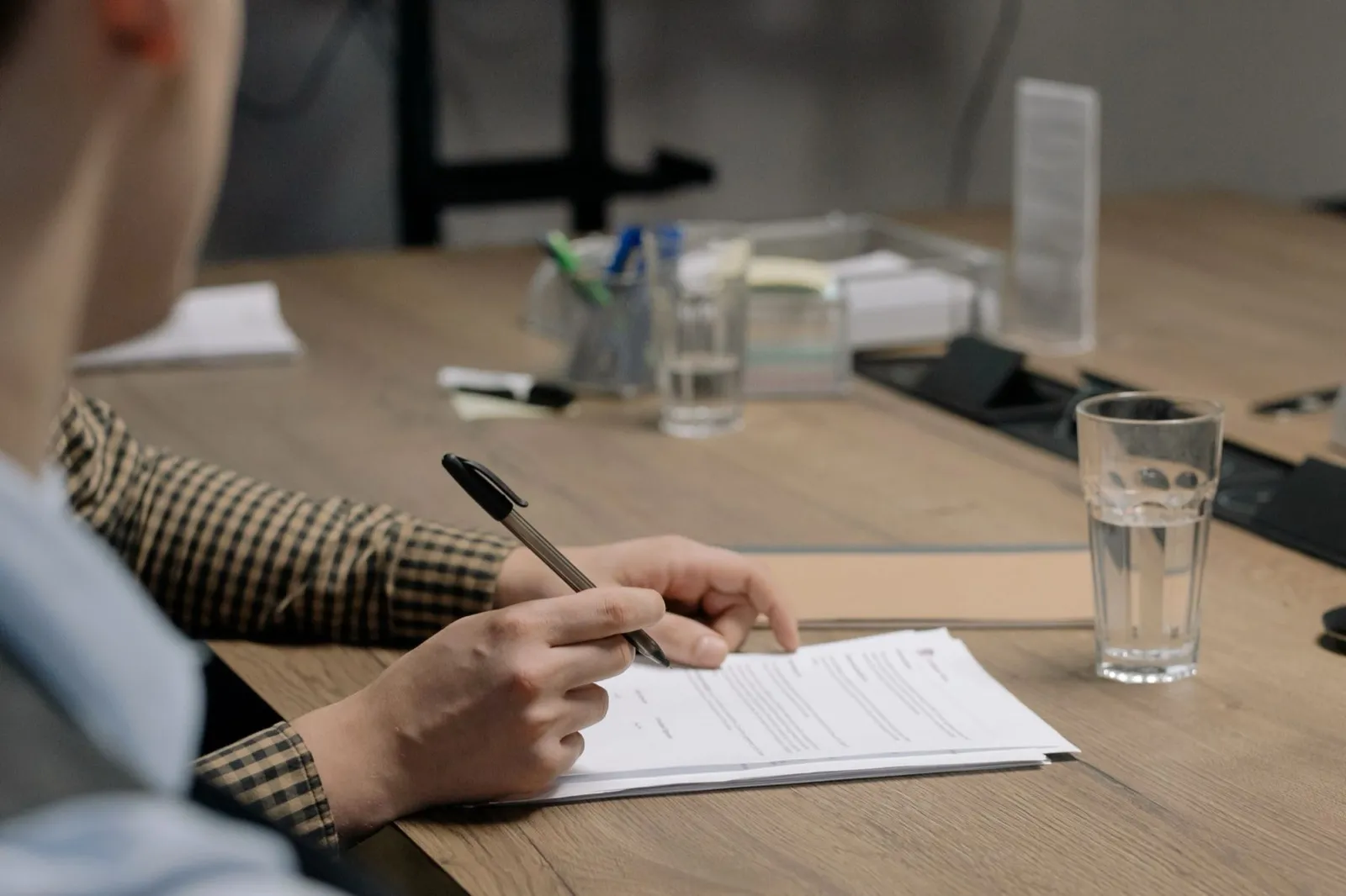 Pessoa preenchendo documentos à mesa